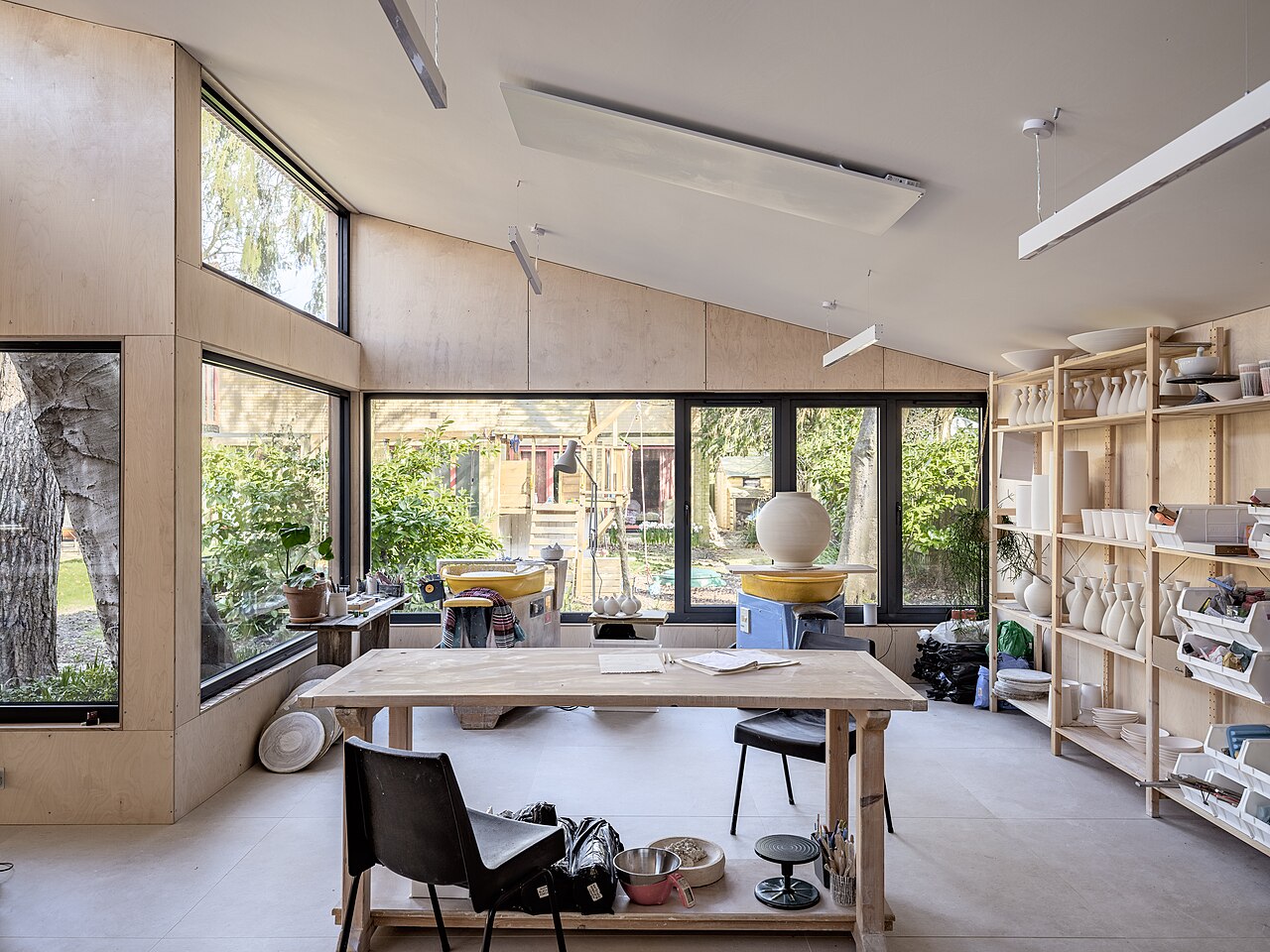 Bright pottery studio with shelves, tools, and ceramic work