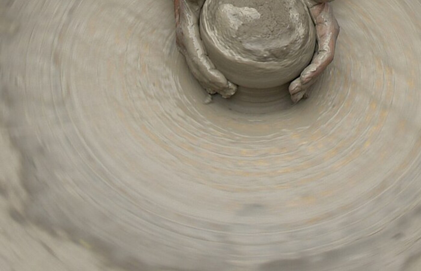 Hands shaping clay on a pottery wheel